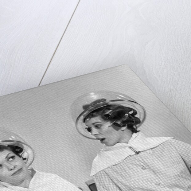 1960s two women sitting under hairdryers gossiping by Anonymous