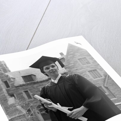 1950s smiling female graduate holding a diploma by Anonymous