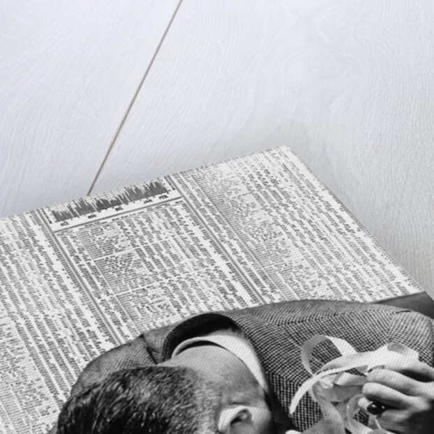 1930s man with head on his desk holding stock ticker tape by Anonymous