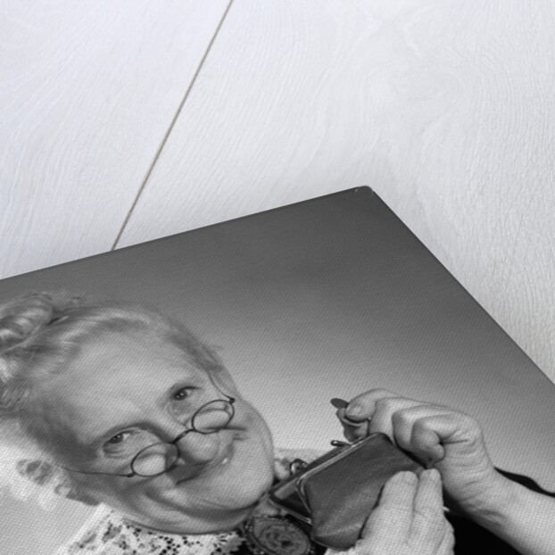 1950s portrait of senior woman putting change into a purse by Anonymous