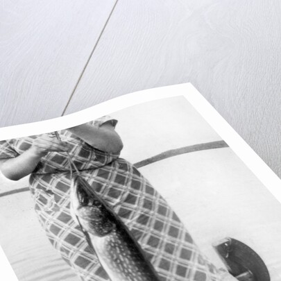 Woman holds on large Northern Pike on a lake pier, ca. 1950. by Anonymous