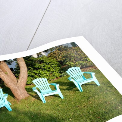 Turquois lawn chairs and green grass at sunset by Anonymous