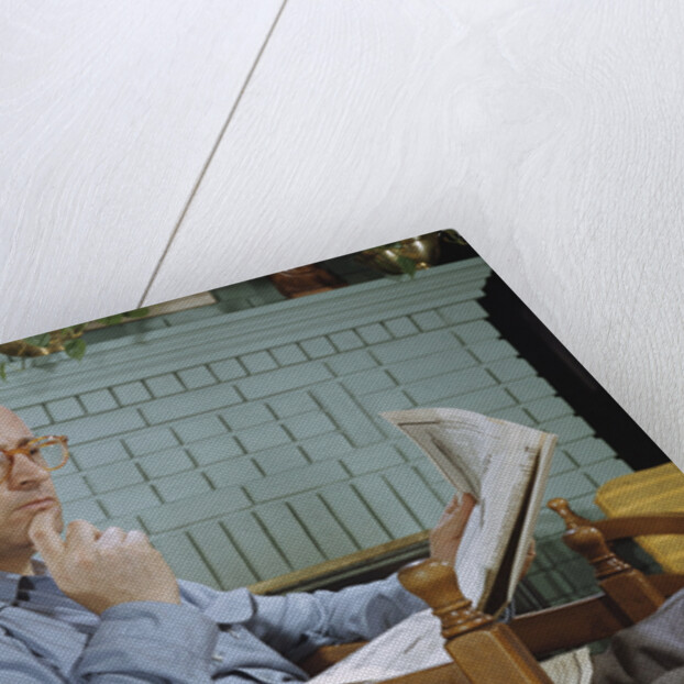 Pensive Man Reading Newspaper in Living Room by Anonymous