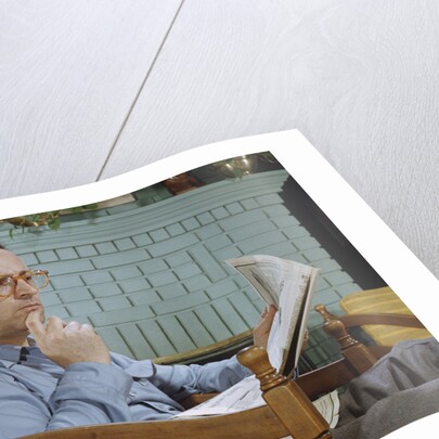 Pensive Man Reading Newspaper in Living Room by Anonymous