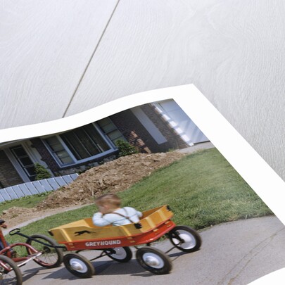 Boy Riding Tricycle and Towing Wagon by Anonymous