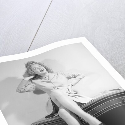 Woman Seated on Desk with Legs Crossed by Anonymous