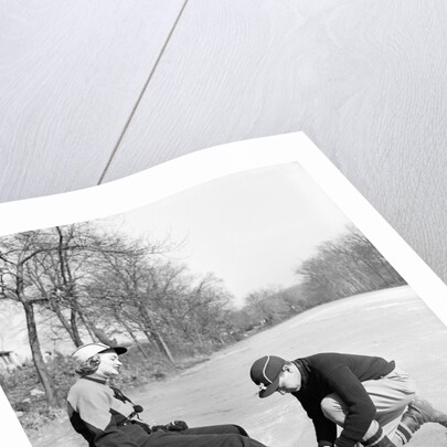 Man Putting on Woman's Ice Skates by Anonymous