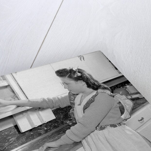 Woman Putting Dishes In Cabinet by Anonymous