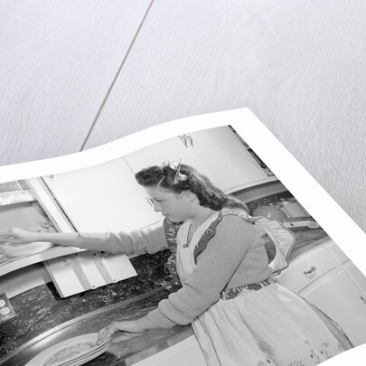 Woman Putting Dishes In Cabinet by Anonymous
