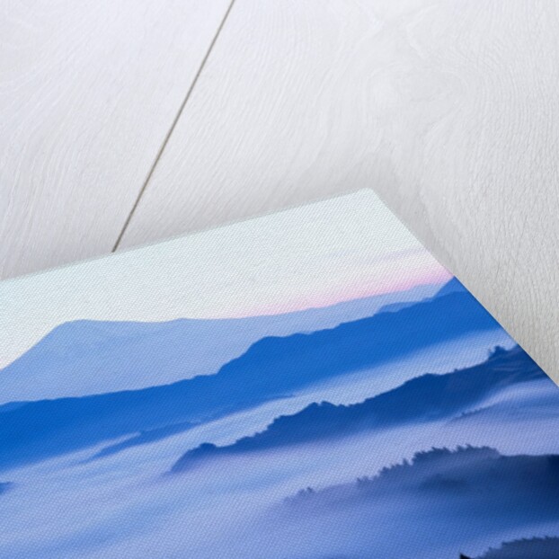 Distant view of Mount Fuji silhouetted against blue sky by Anonymous
