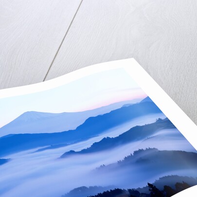 Distant view of Mount Fuji silhouetted against blue sky by Anonymous