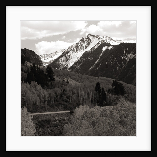 High angle view of road winding up the side of a hill with mountains in the distance by Anonymous