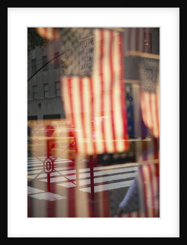 Yellow taxis in intersection reflected in window with American flags by Anonymous