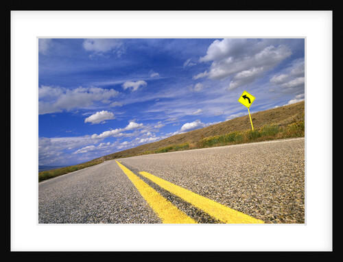 Curving rural highway under cumulus clouds in Colorado prairie by Anonymous