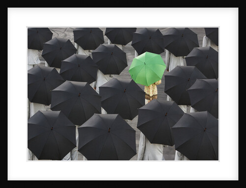 Green umbrella among group of black by Anonymous