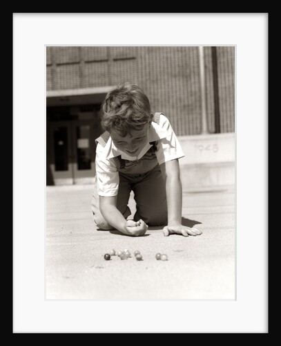 1950s Boy Ready To Shoot Kneeling On School Yard Ground Playing Game Of Marbles by Anonymous