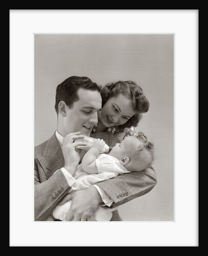 1940s Father Cradling Baby Daughter Feeding Her Bottle With Mother Looking Over His Shoulder by Anonymous