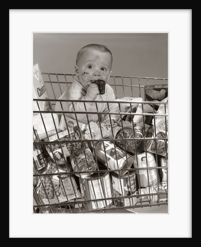 1960s Baby Sitting In Supermarket Cart Full Of Cans Eating Candy Bar With A Messy Face by Anonymous