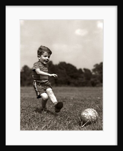 1940s Boy Kicking Ball In Grassy Field by Anonymous