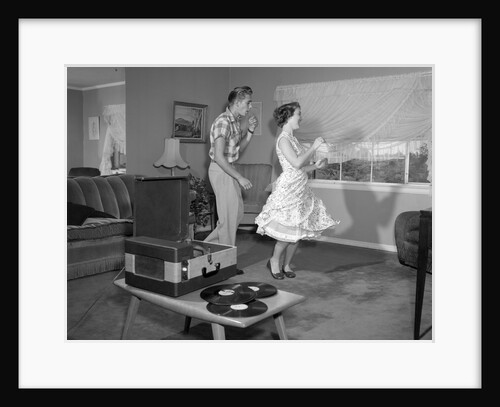 1950s Laughing Teenage Couple Dancing To The Phonograph Playing 78 Rpm Records In Living Room by Anonymous