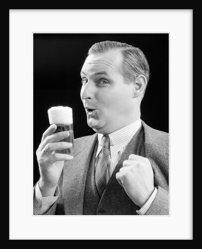 1930s Man Holding Full Foamy Glass Of Beer Making A Funny Face With His Thumb Hooked Confidently Under His Vest by Anonymous