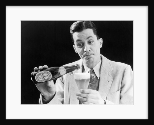 1930s Man Pouring Beer From Bottle Into Glass Look Of Anticipation Wearing Suit Tie Sweater by Anonymous