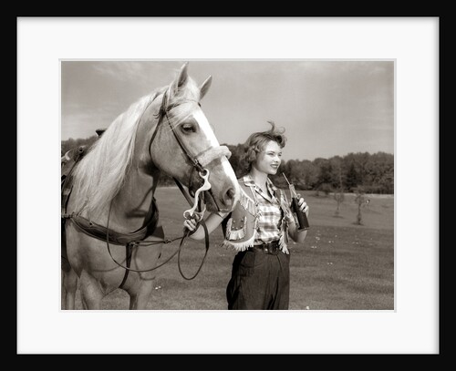 1950s Teenage Girl Western Wear Holding Horse Halter Drinking Carbonated Beverage From Bottle by Anonymous