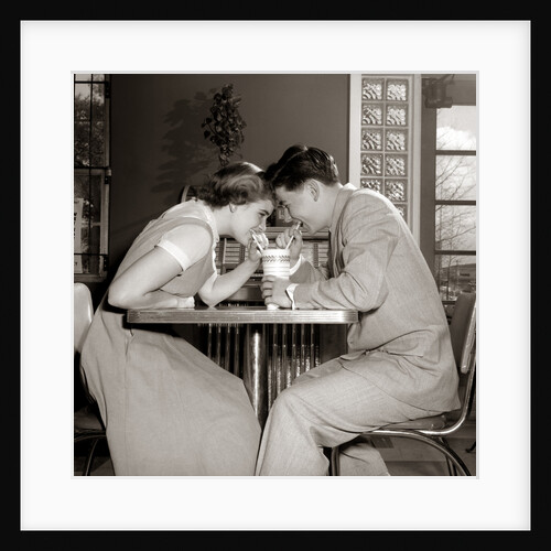 1950s 1960s Laughing Teenage Boy and Girl Sharing Drink Together With Two Straws In Soda Shop by Anonymous