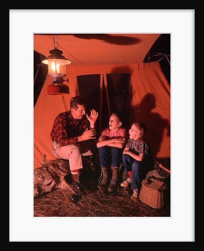 1960s 1970s Grandfather Telling Scary Story To Boys By Tent At Night Campsite In Shadows by Anonymous