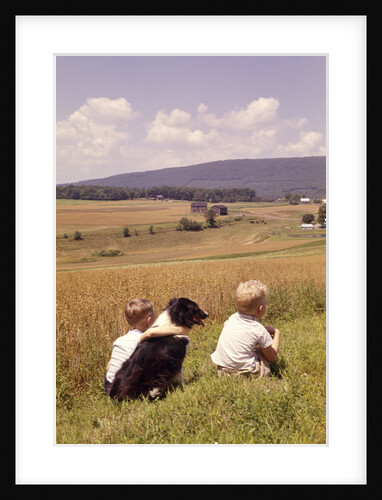 1960s Back Of Two Boys With Black And White Dog Sitting Hillside Field Looking Down To Farm by Anonymous