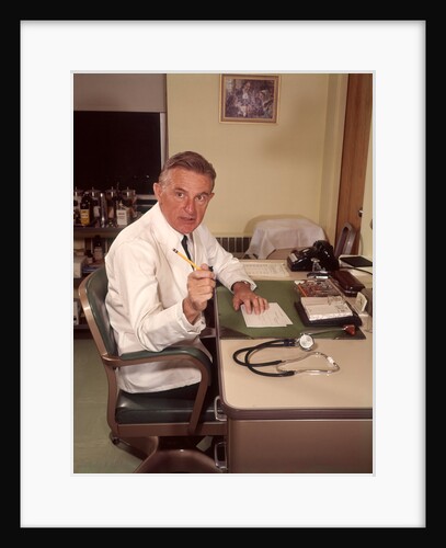 1960s Man Doctor Pointing Gesturing With Pencil Seated At Desk In Office by Anonymous