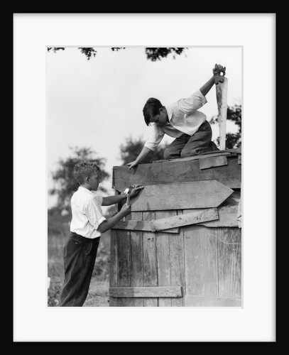 1930s Pair Of Boys Building Shack One Nailing Board To Side One On Roof With Saw by Anonymous