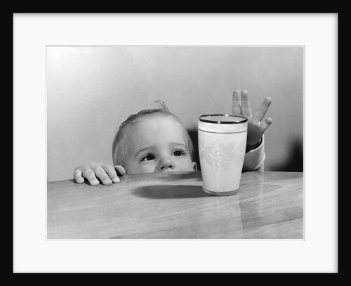 1950s Toddler Reaching Up To Table To Grab Milk Glass by Anonymous