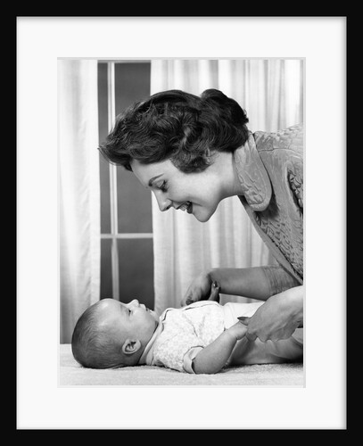 1950s 1960s Mother At Baby Lying On Table Indoor by Anonymous