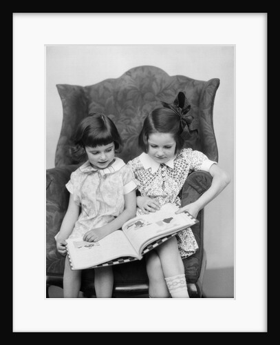 1920s 1930s Two Girls Sitting Side By Side In Chair Reading Book by Anonymous