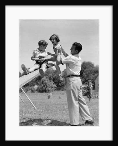 1950s Father Lifting Son And Daughter Onto A Playground Seesaw Outdoor by Anonymous