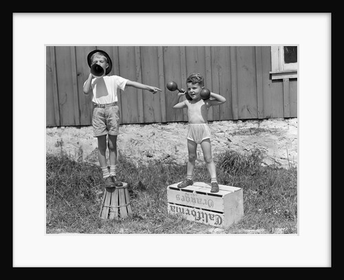 1930s 1940s Boys Playing Carnival Strongman One Lifting Dumbbells Other Announcing Act Through Megaphone by Anonymous