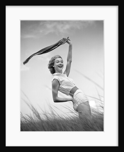 1950s 1960s Young Woman Bending Back Holding Scarf In The Wind Standing On Grassy Beach Dune by Anonymous