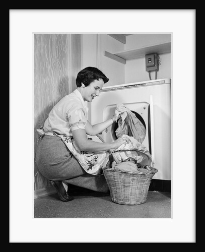 1950s Woman Kneeling Removing Clothes Laundry From Automatic Dryer by Anonymous