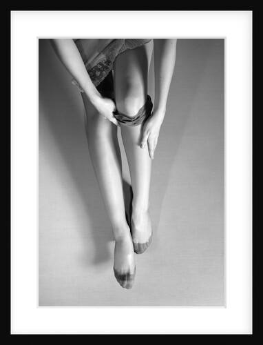 Woman's Hands Putting A Pair Of Sheer Stockings On Her Legs by Anonymous