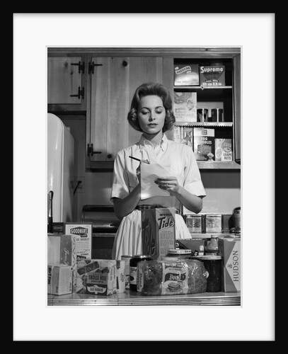 1960s Woman Housewife In Kitchen Checking Grocery Food Shopping List by Anonymous