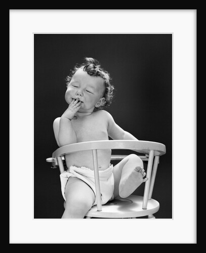 1940s 1950s Baby Sitting Backwards In High Chair With One Leg In Air Eyes Closed and Hand On Mouth by Anonymous