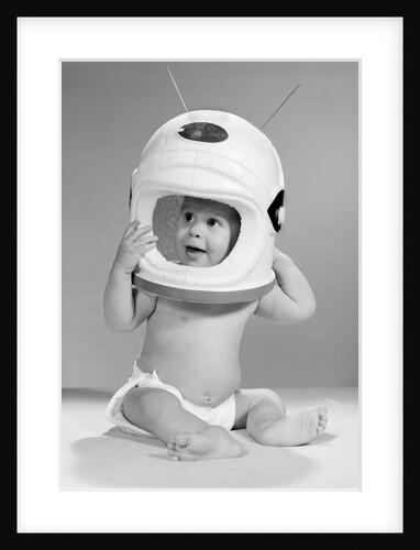 1960s Baby In Diaper Seated Holding Astronaut Helmet With Antennae On Head by Anonymous