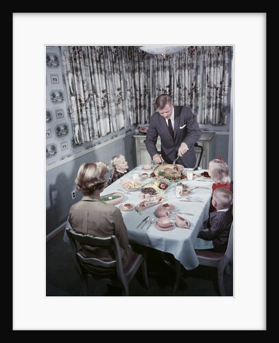 1950s Family 5 Sitting At Dining Room Table Dad Carves Turkey At Head Of Table by Anonymous