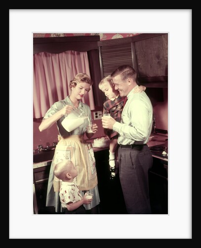 1950s Family In Kitchen Mother Pouring Milk From Pitcher For Dad And Kids by Anonymous