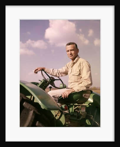 1960s Portrait Man Farmer Sitting On Green Tractor Smoking Cigarette by Anonymous