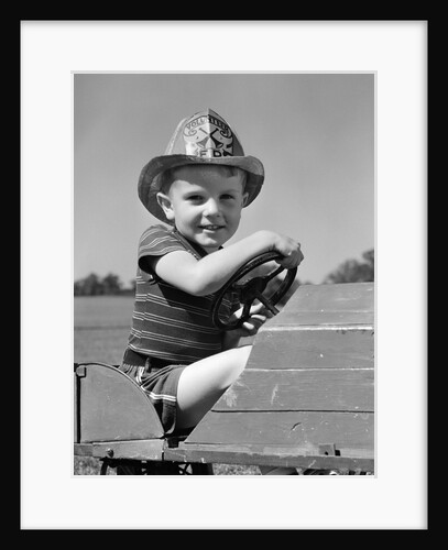 1940s Boy Playing Fireman In Toy Fire Truck Wearing Fireman's Safety Hat Holding Steering Wheel by Anonymous