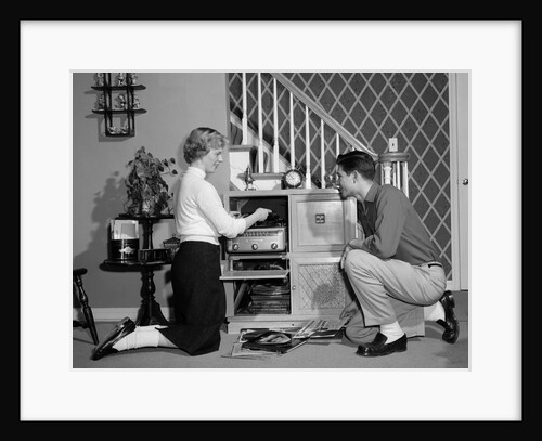 1950s Teenage Couple Playing Hi-Fi Records On Console Phonograph In Living Room by Anonymous