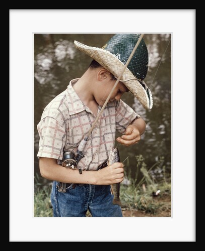 Boy Wearing Straw Hat Removing Hook From Mouth Of Fish Outdoor by Anonymous