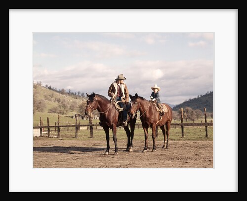 1970s Father And Son Sitting Together On Horses By Corral Wearing Hats by Anonymous